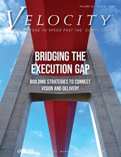 Cover of Velocity magazine featuring a view from underneath a red and white bridge against a blue sky with clouds. The main headline reads: Bridging the Execution Gap. Building strategies to connect vision and delivery.